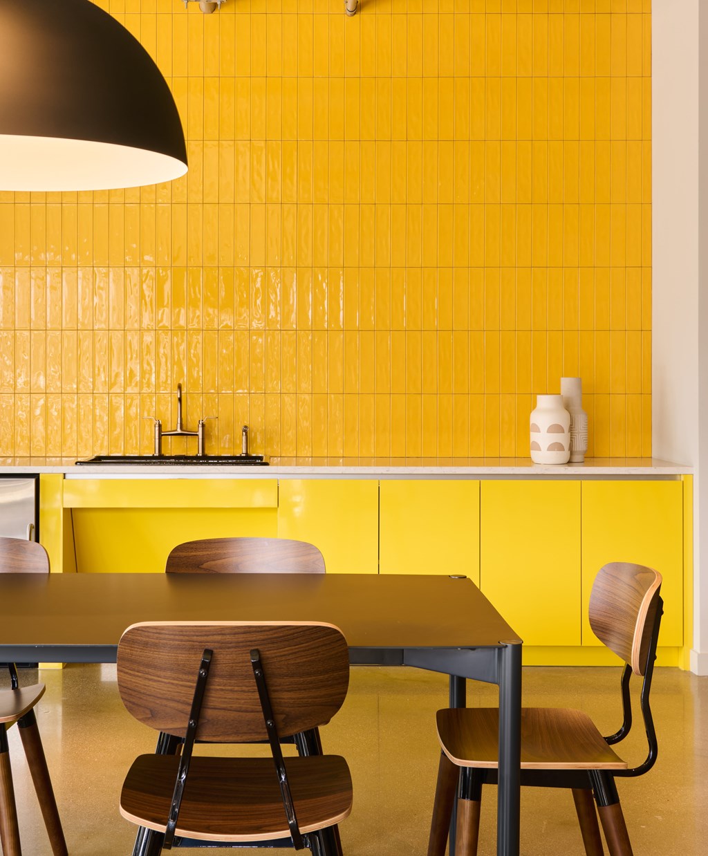 A yellow tiled wall behind a table with chairs.