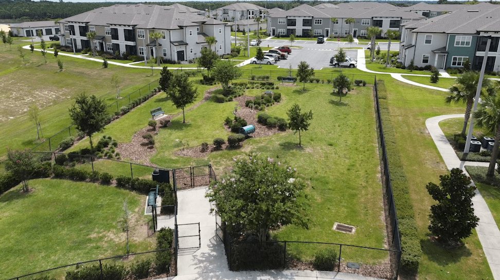 A park area with a playground and a walking path in front of apartment buildings.