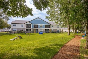 A building with a blue roof is surrounded by a grassy area and trees.