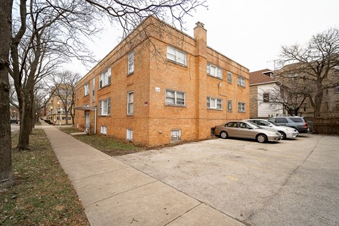 A brick building with a parking lot in front.