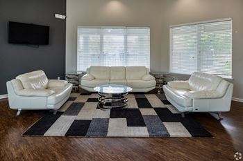 A living room with white leather furniture and a black and white rug.