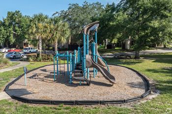 A playground with a blue slide and a brown sandbox.