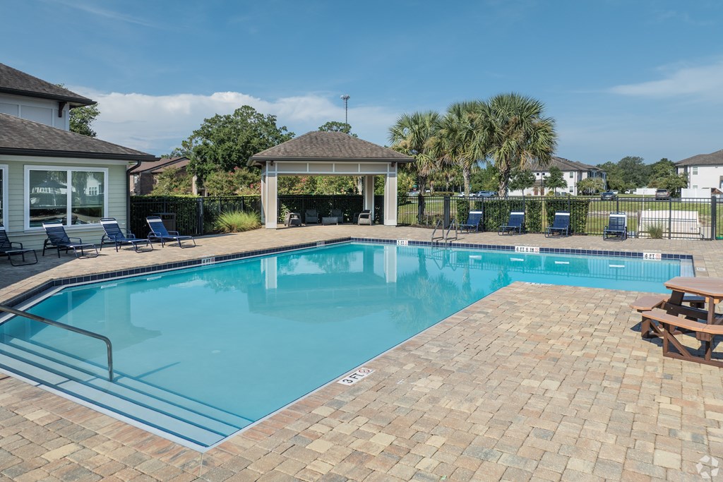 A swimming pool surrounded by a brick patio and a gazebo.