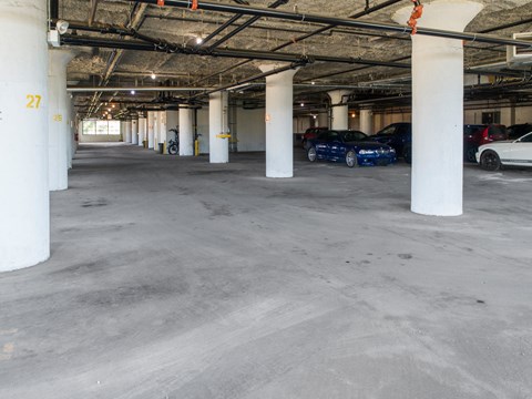 a parking garage with white pillars and cars parked in it