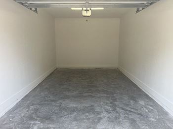 A large empty room with a concrete floor and white walls.