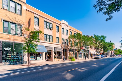 A street view of a city with buildings on the side and cars parked on the side of the road.
