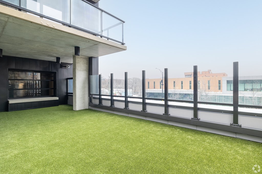 A balcony with a glass railing and a green lawn.