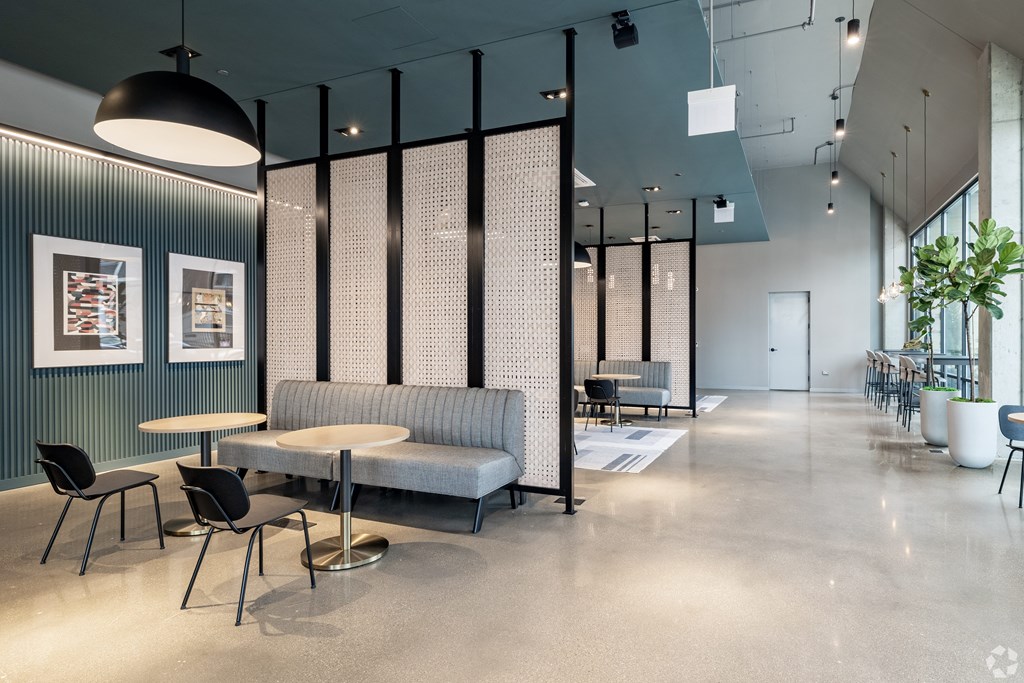 A modern office space with a grey sofa, black chairs, and a glass partition.