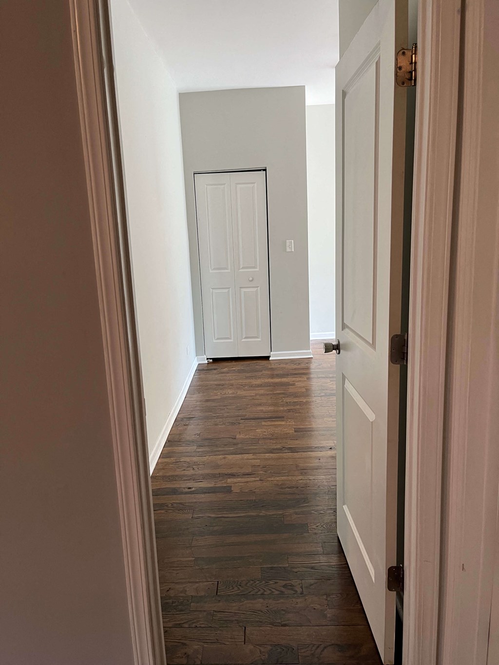 a hallway with wood floors and a white door