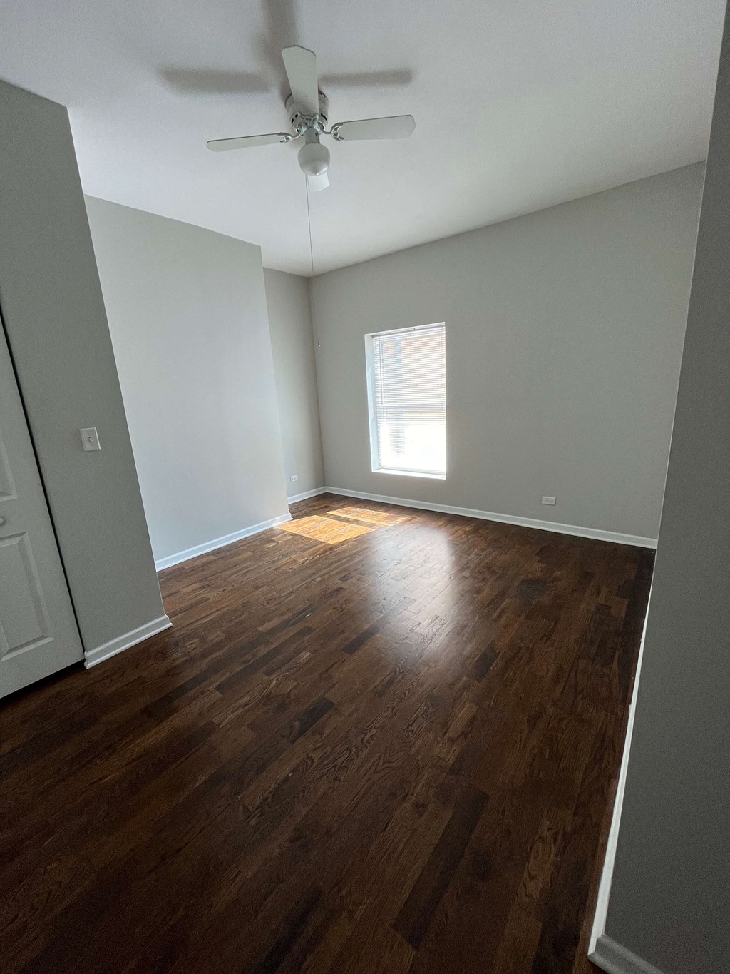 an empty living room with wood floors and a ceiling fan