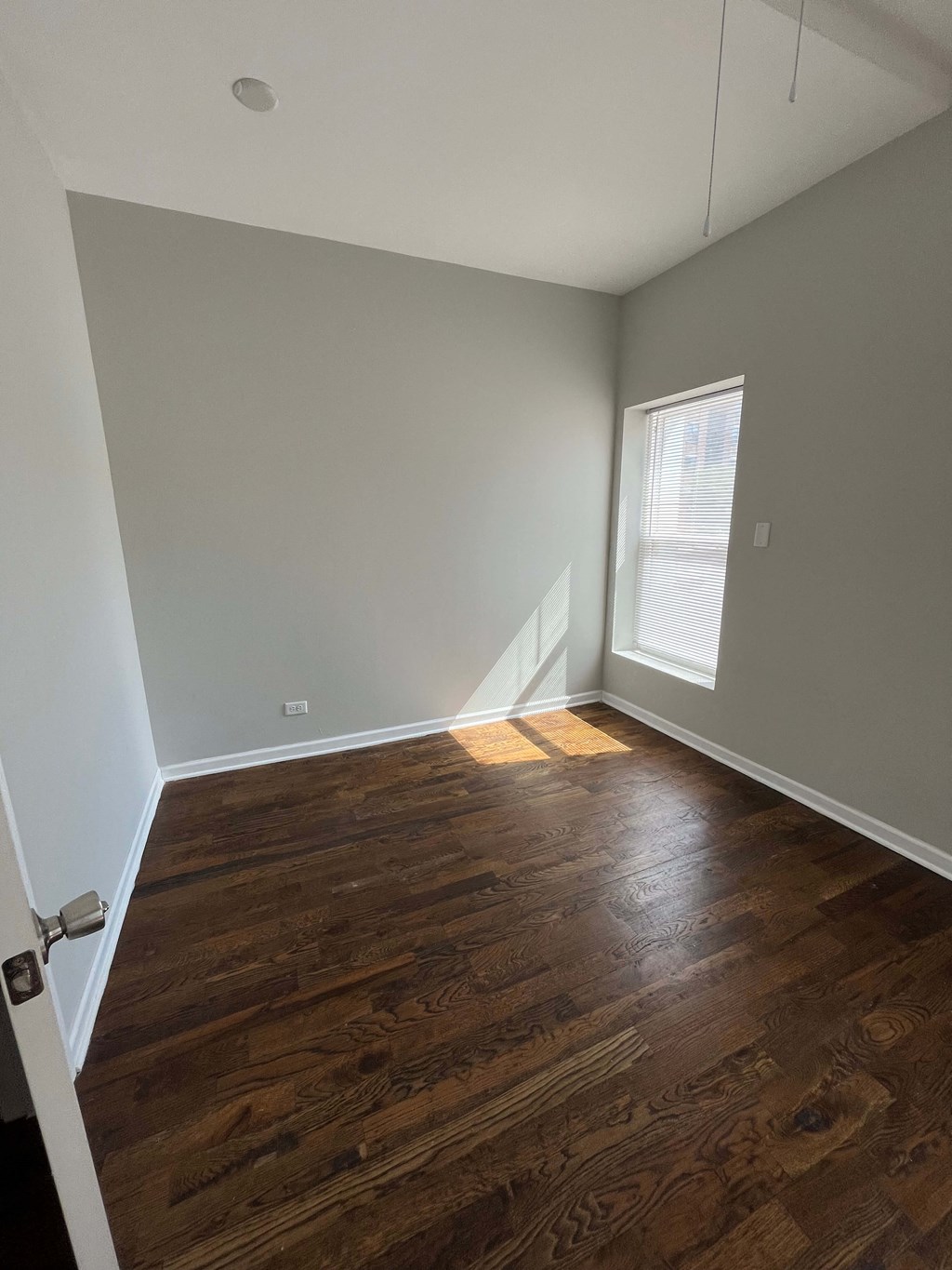 an empty living room with wooden floors and a window