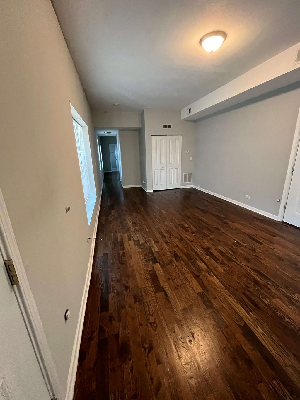 a living room with a hard wood floor and a door into a bedroom
