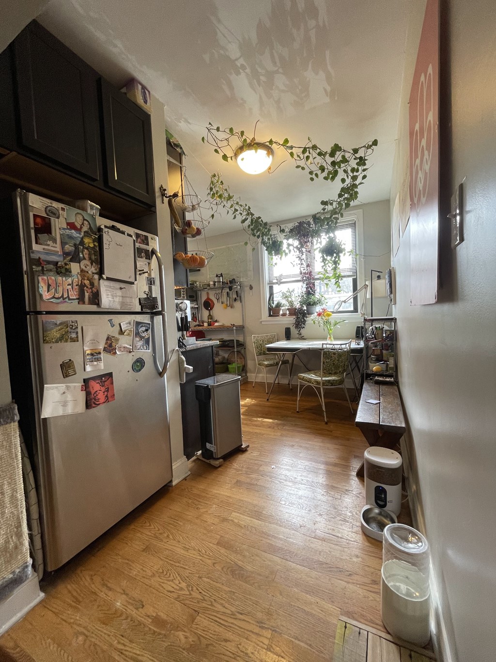 A kitchen with a refrigerator covered in magnets and a dining table with chairs.