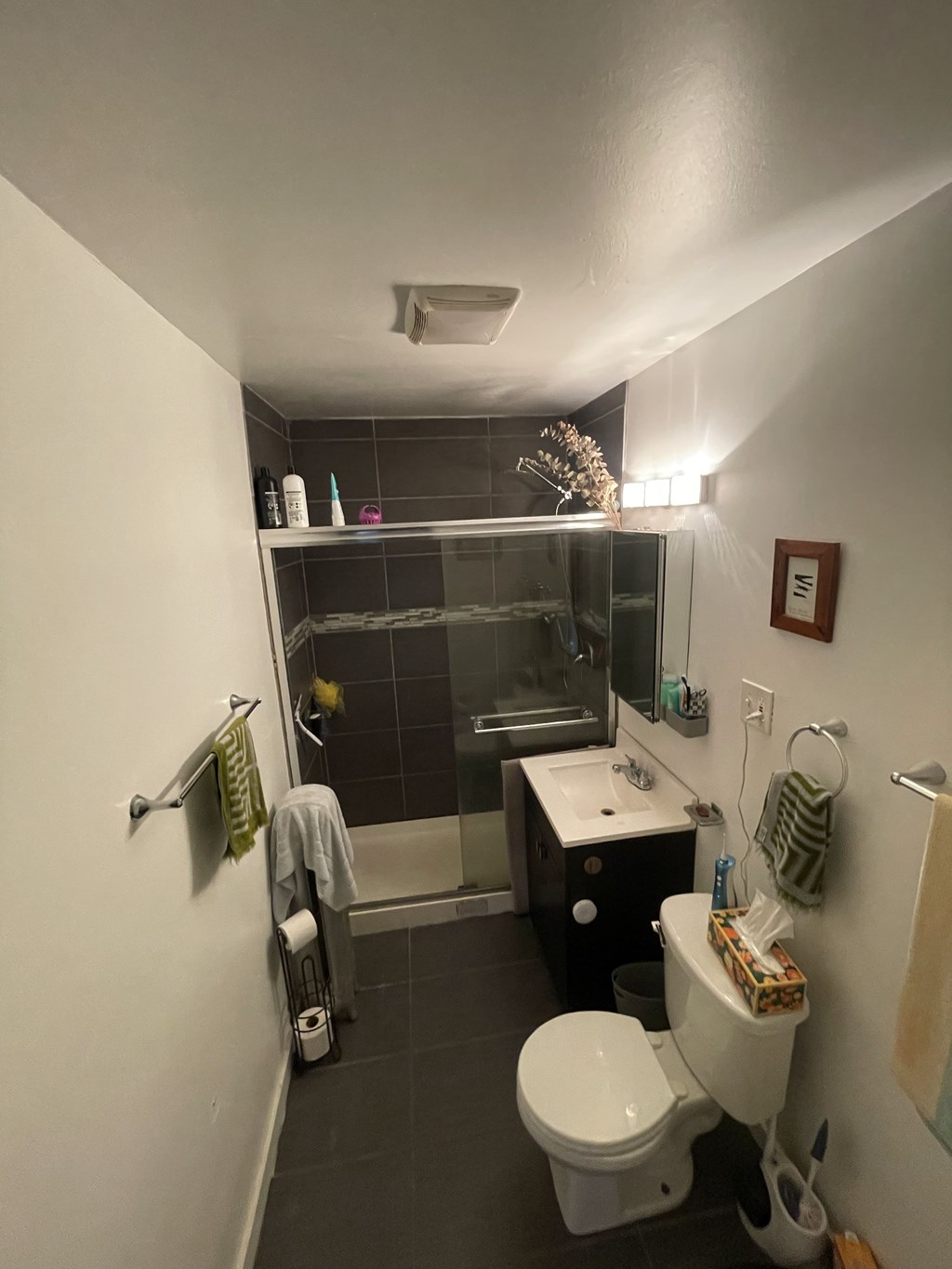 A small bathroom with a toilet, sink, and shower.