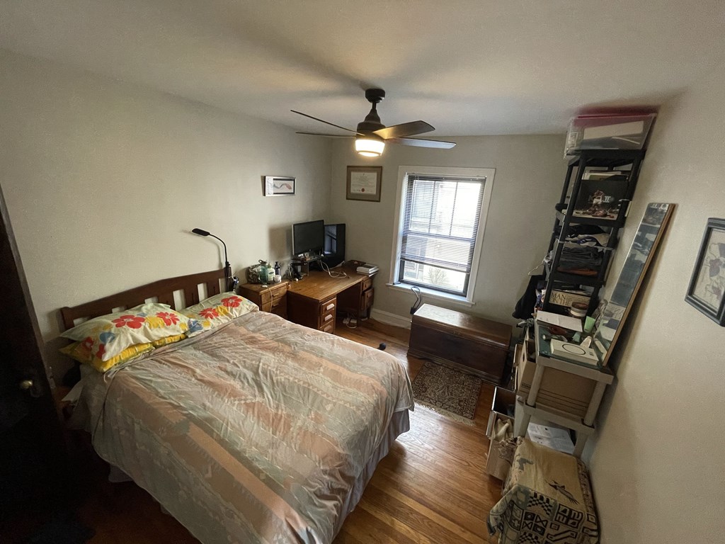 A bedroom with a bed, a ceiling fan, and a window.