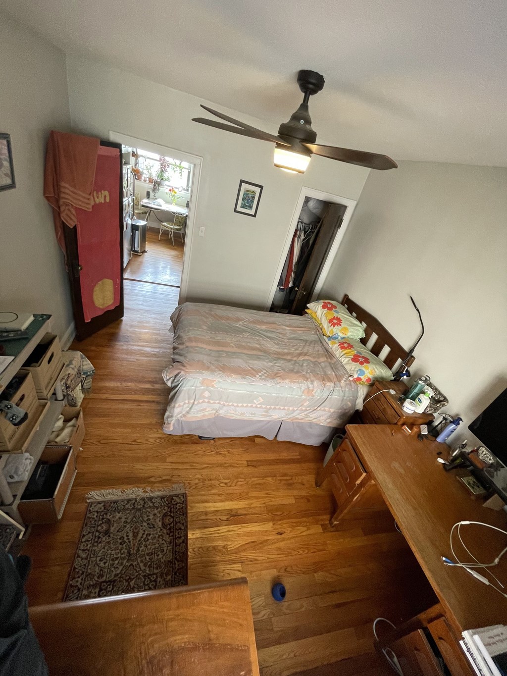 A bedroom with a bed, dresser, and ceiling fan.