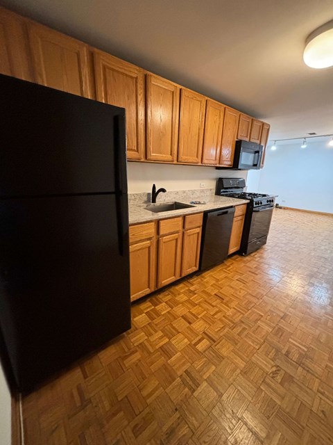 a kitchen with wooden cabinets and a black refrigerator