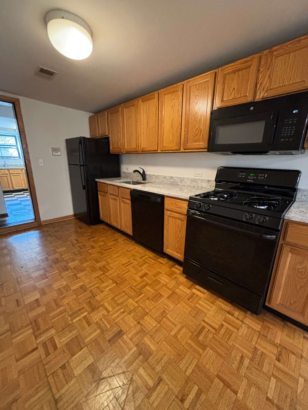 an empty kitchen with wood flooring and black appliances