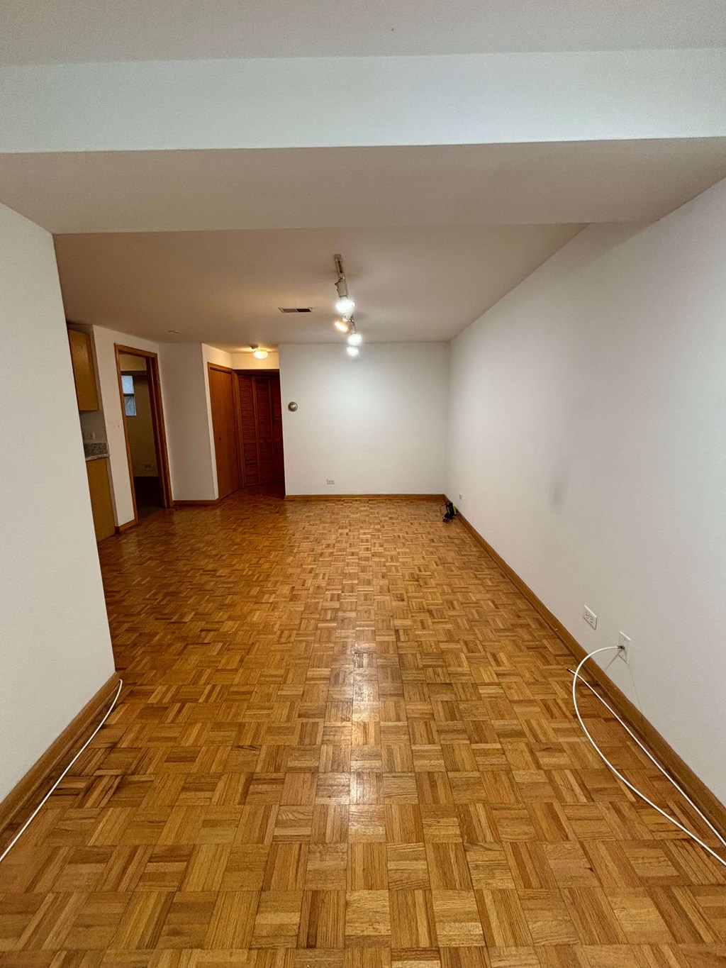 an empty living room with wood flooring and white walls