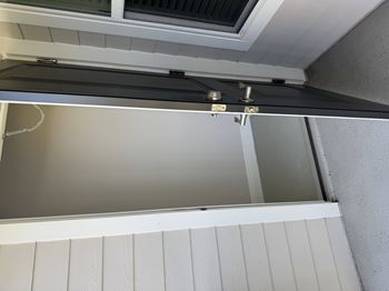 A white wooden shelf with a glass door and a metal bracket.