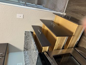 A kitchen with a stainless steel oven and wooden cabinets.
