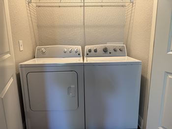 A pair of front loading washing machines in a laundry room.