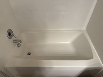 A white bathtub with a shower head and faucet.