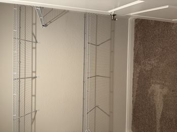 A wall with a metal grid and a brown carpet.