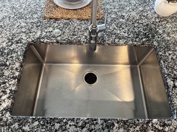 A stainless steel kitchen sink with a hole in the middle.