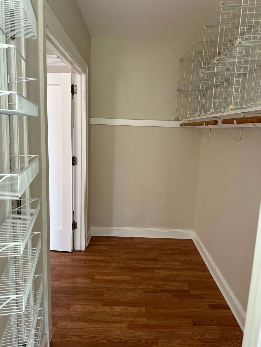 a small room with a closet and a door to a room with wooden flooring