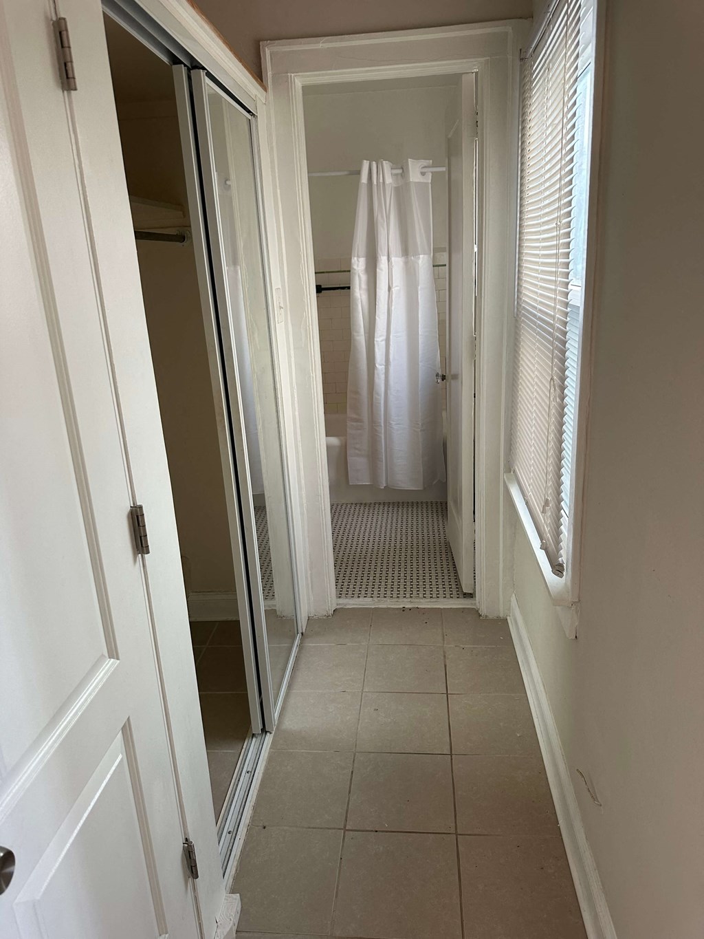 a hallway with a door to a bathroom and a shower curtain