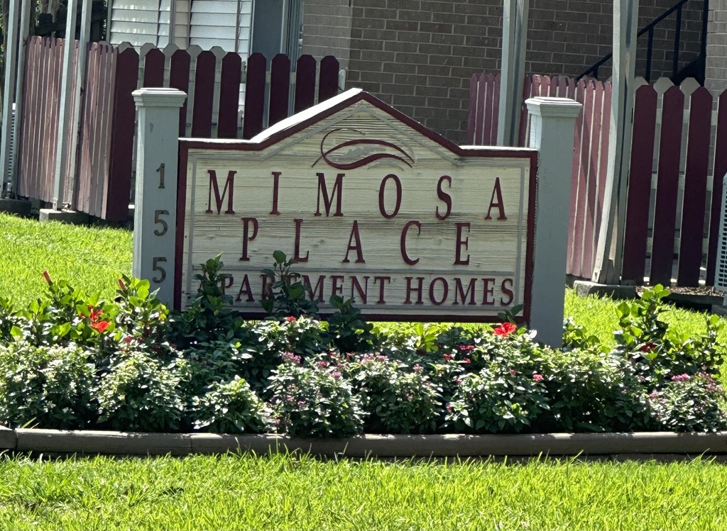 a sign in front of a building that says mimosa place apartment homes