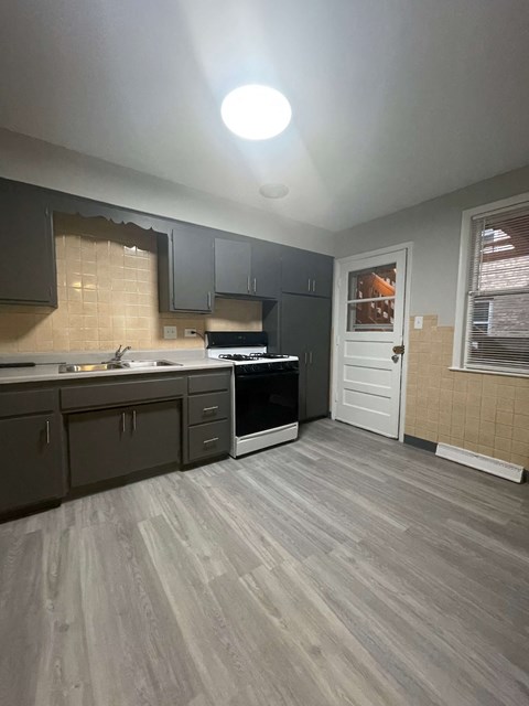 A kitchen with a white door and a stove top oven.