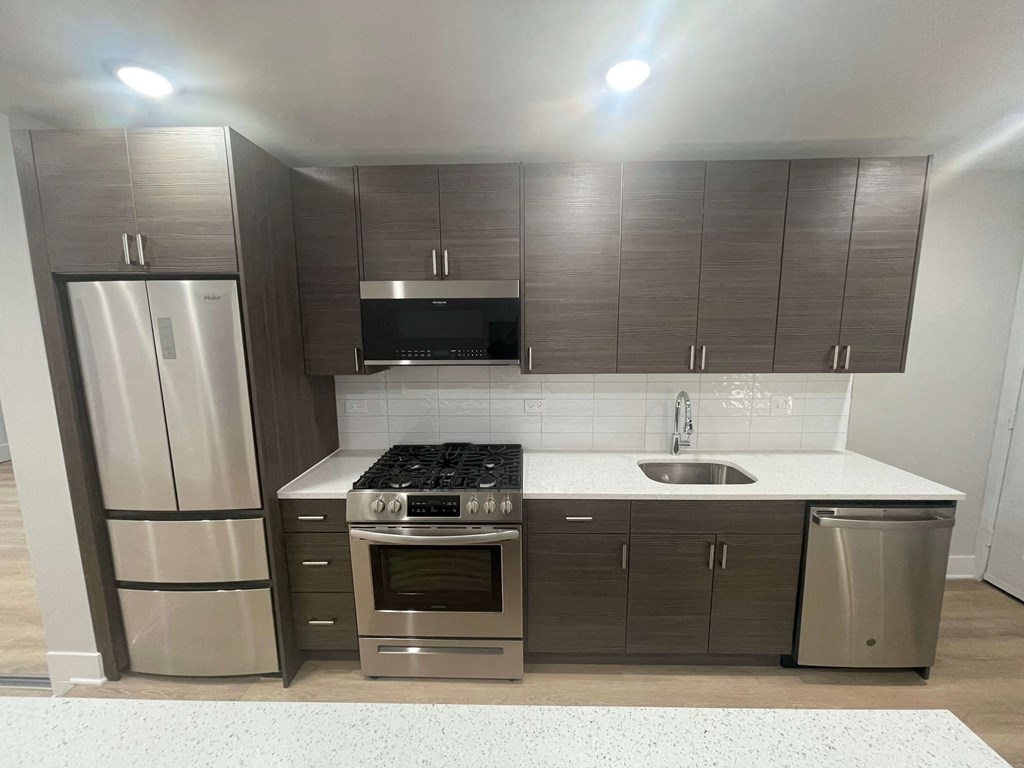 an empty kitchen with stainless steel appliances and wooden cabinets