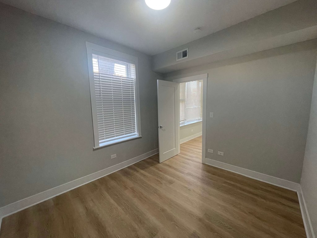 a living room with a hardwood floor and a door to a bedroom