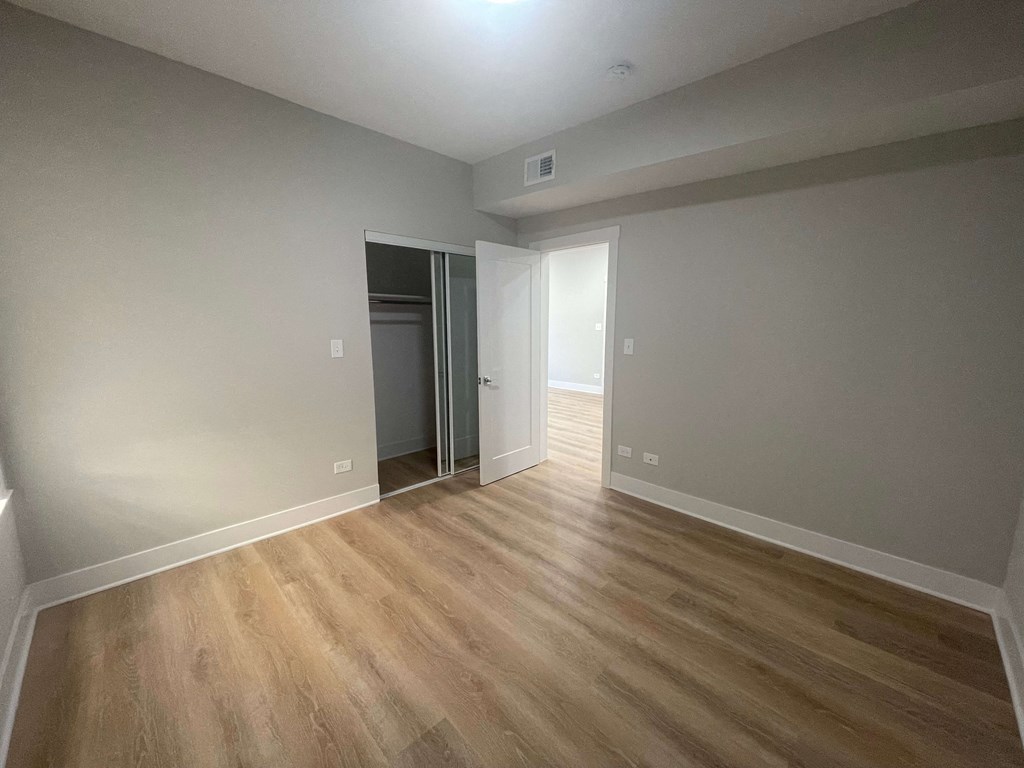 a living room with wood flooring and a door to a bedroom