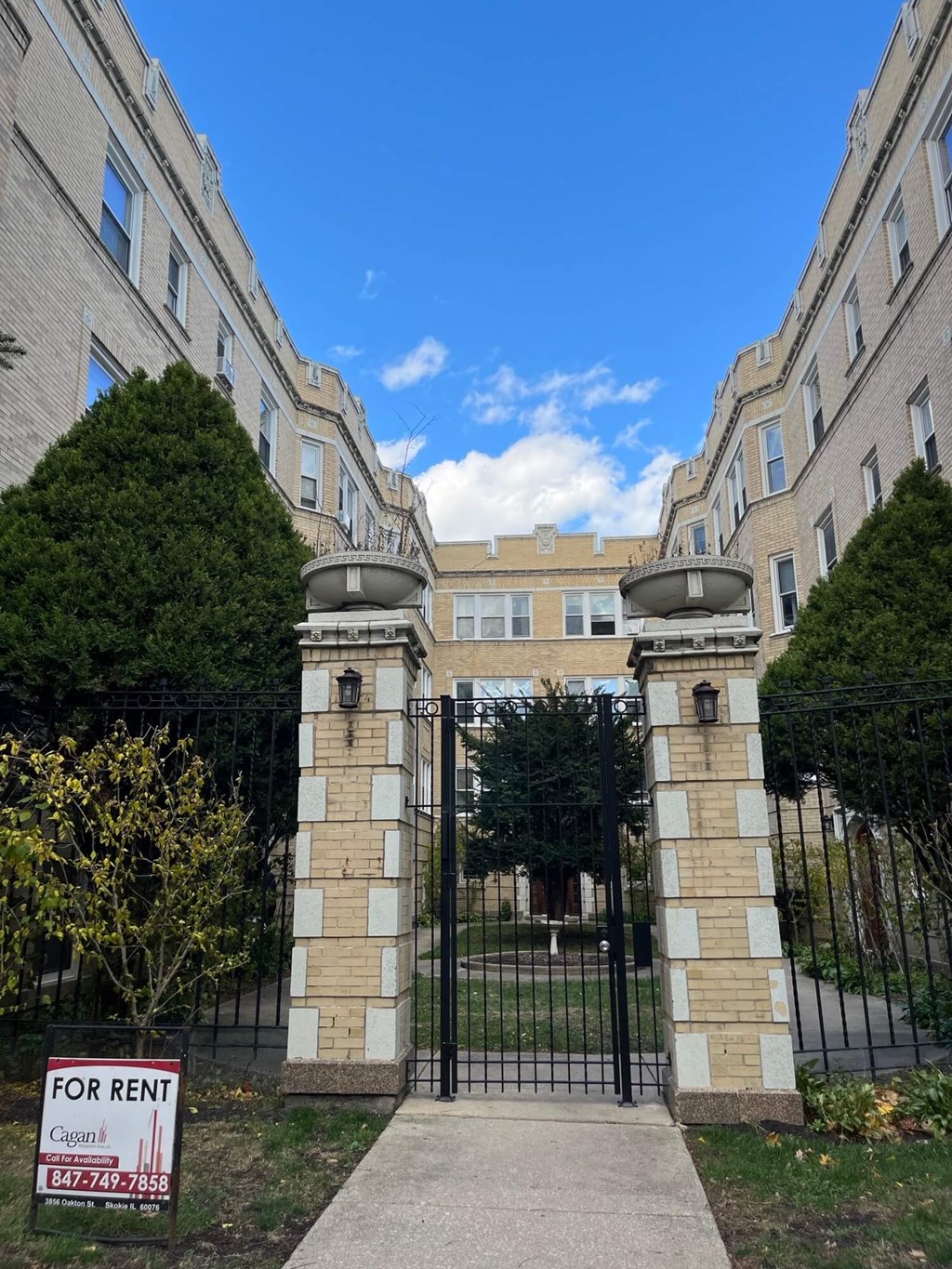 an apartment building with a for rent sign in front of a gate