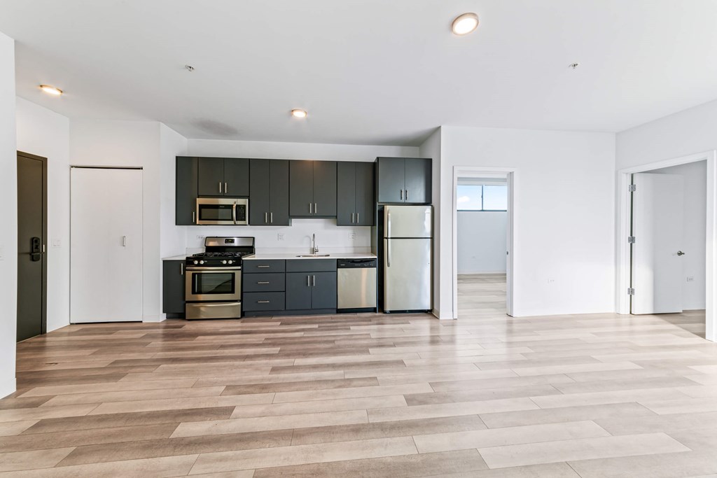 A modern kitchen with dark grey cabinets and a wooden floor.