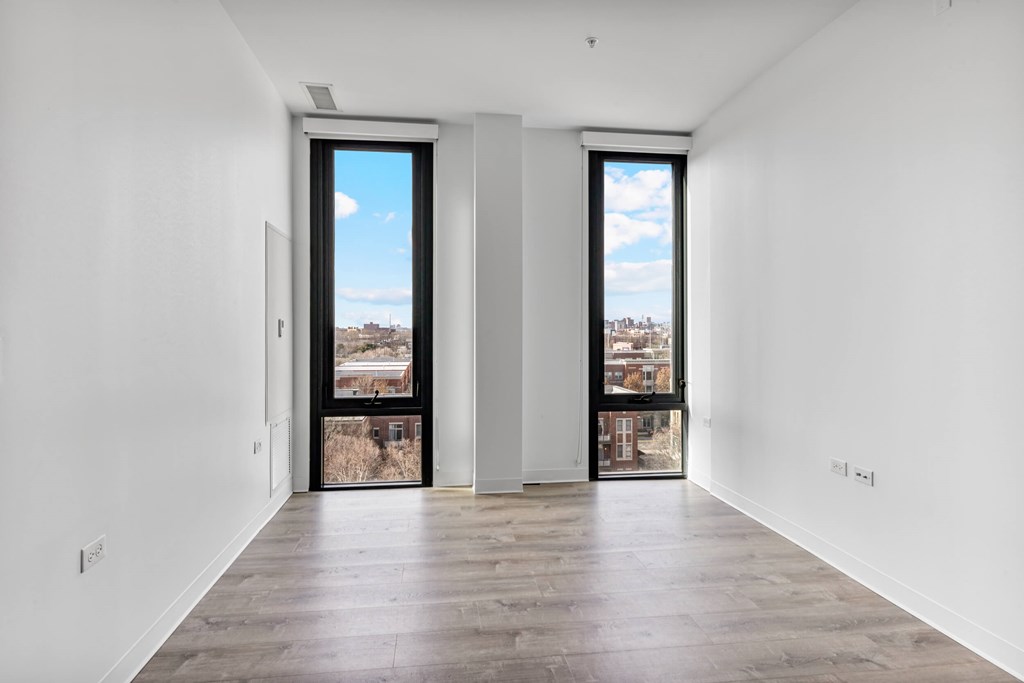 A large empty room with a view of the city through the windows.