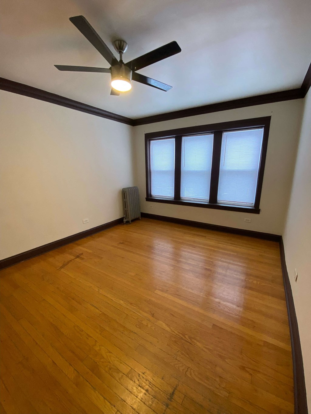 an empty living room with wooden floors and a ceiling fan