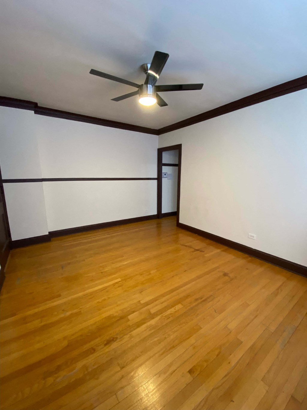 an empty room with a ceiling fan and wooden floors