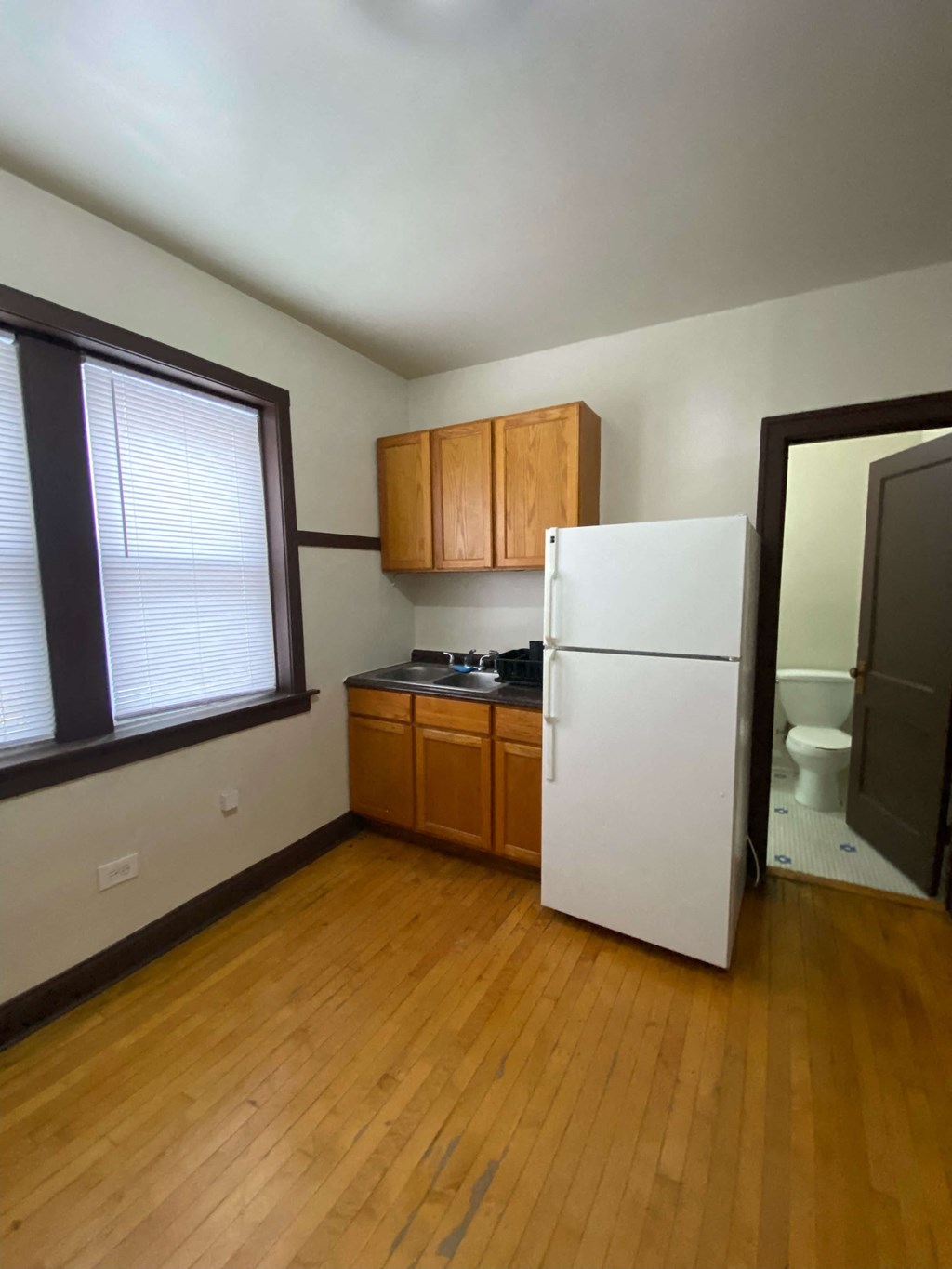 an empty kitchen with a refrigerator and a window