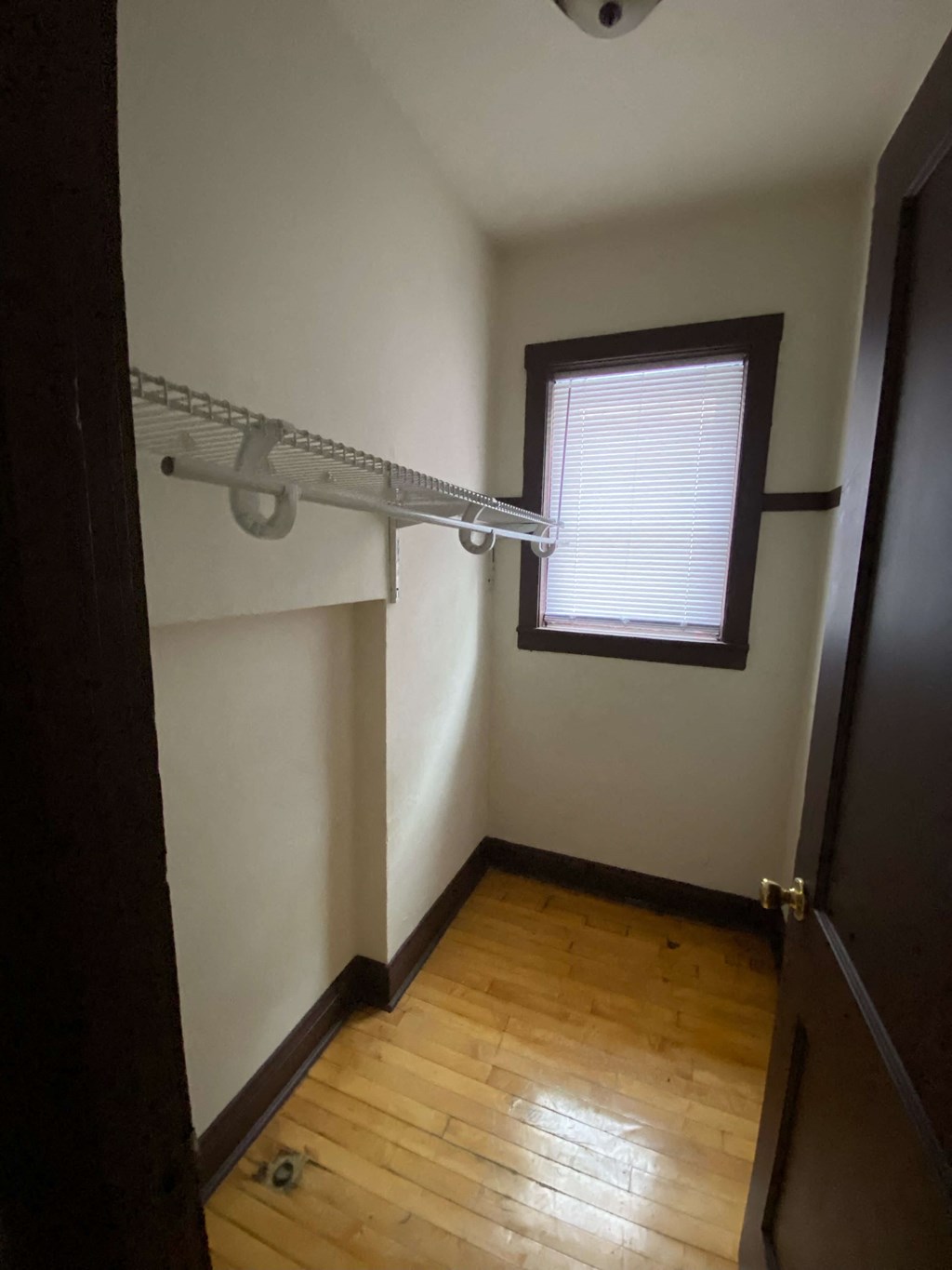 an empty room with a window and a clothes rack
