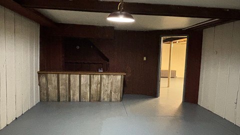 A room with a wooden bar counter and a light hanging from the ceiling.
