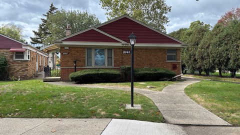 A red brick house with a black lamp post in front.