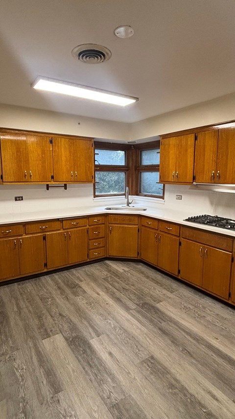 A kitchen with wooden cabinets and a grey floor.
