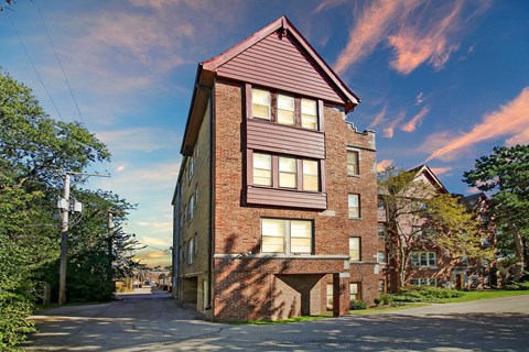 a three story brick house with a pink roof on a street