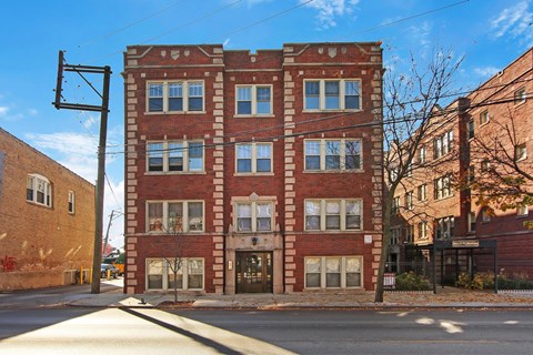 A red brick building with a black awning on the corner of a street.