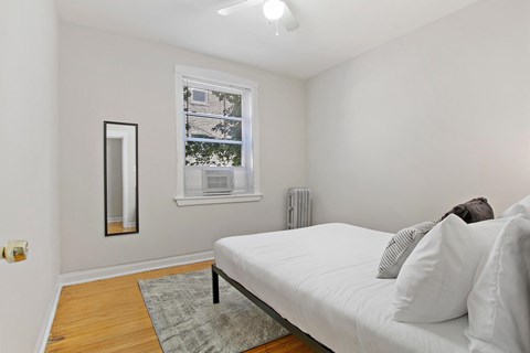 A bedroom with a white bed and a window with blinds.