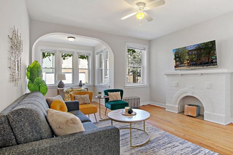 A living room with a grey couch and a fireplace.